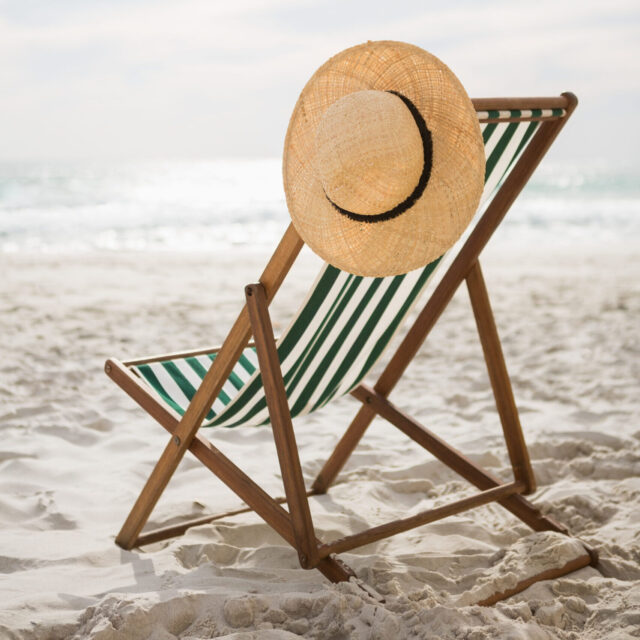 Straw hat kept on empty beach chair at tropical sand beach